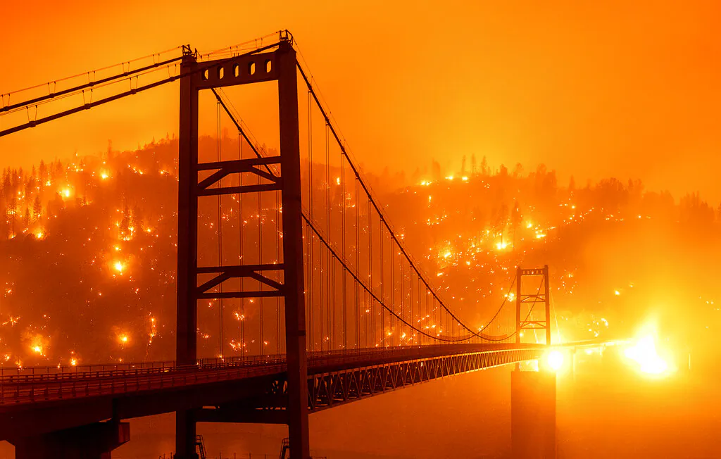 In this image taken with a slow shutter speed, embers light up a hillside behind the Bidwell Bar Bridge as the Bear Fire burns in Oroville, Calif., on Sept. 9, 2020. (AP Photo/Noah Berger)
