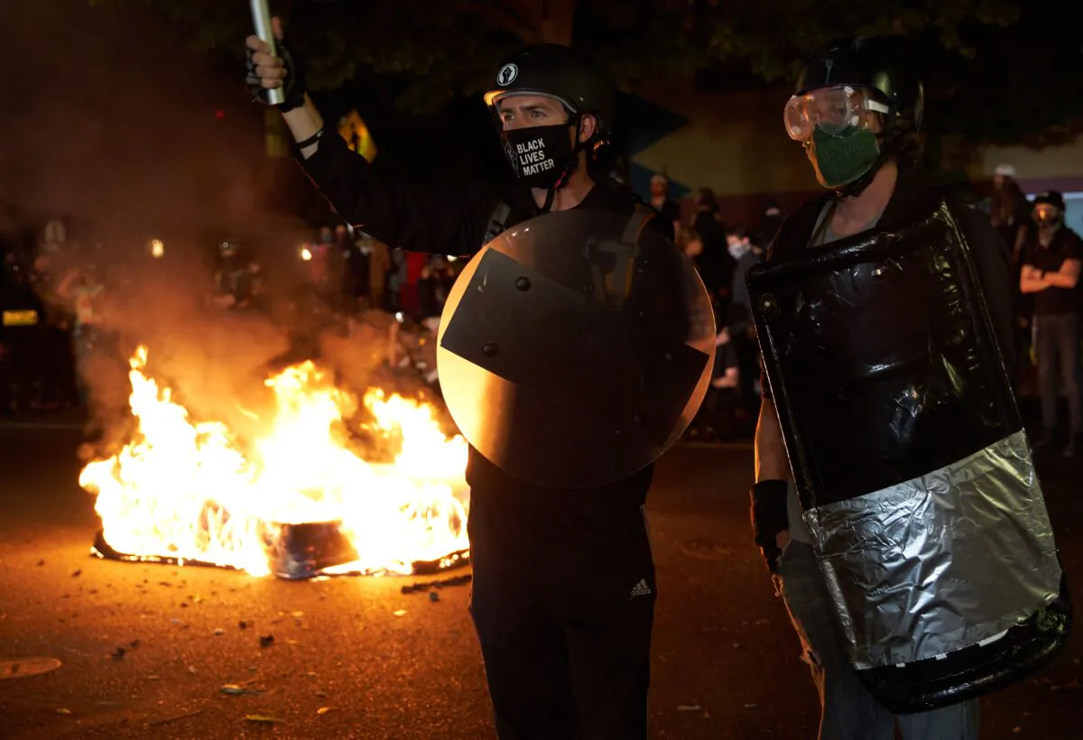People stand near a mattress that was set on fire during a riot in Portland, Ore., on Sept. 6, 2020. (Allison Dinner/AFP via Getty Images)