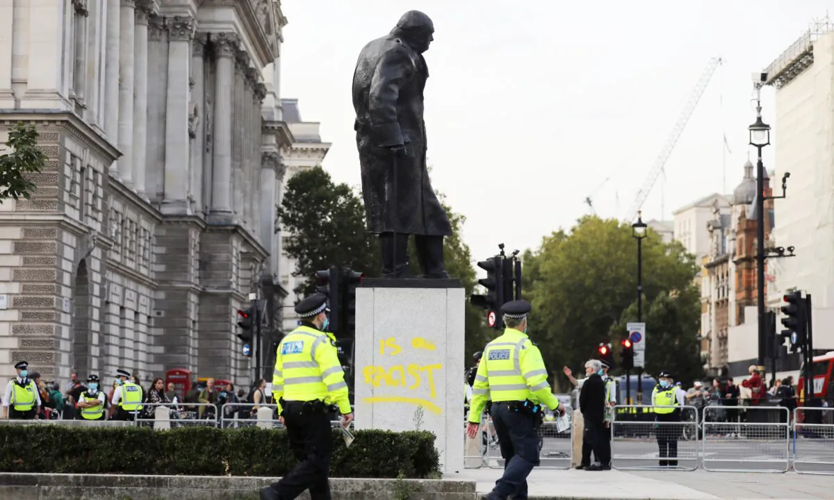 Police officers walk by the defaced statue of Winston Churchill, in London, on Sept. 10, 2020. (Simon Dawson/Reuters)
