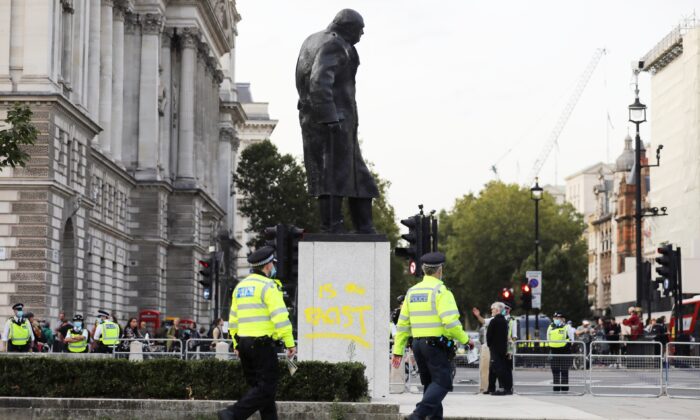 Police officers walk by the defaced statue of Winston Churchill, in London, on Sept. 10, 2020. (Simon Dawson/Reuters)