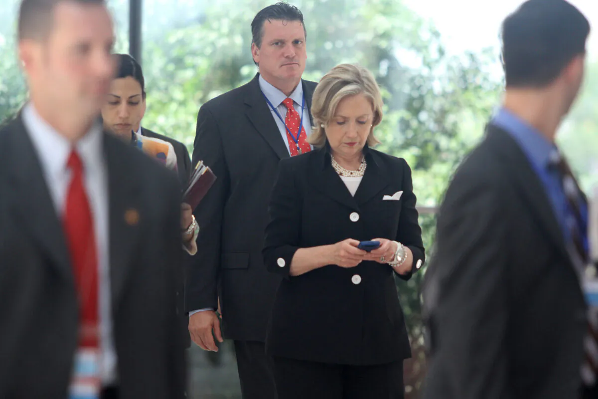 Then-Secretary of State Hillary Clinton (C) looks at her mobile phone in Hanoi, Vietnam, on July 23, 2010. (Na Son Nguyen/AFP via Getty Images)