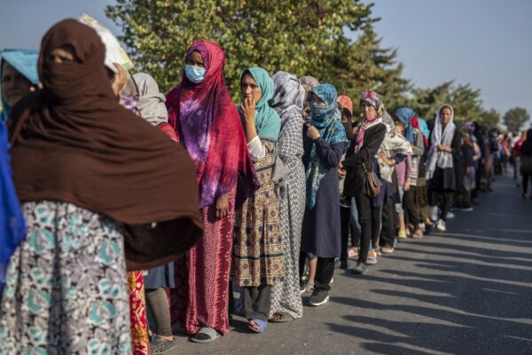 Migrants wait in a queue for food distribution