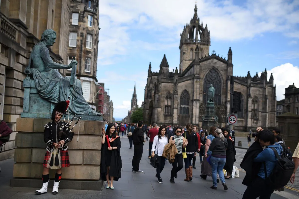 A street performer plays the bagpipes next to a statue of Scottish philosopher David Hume on the Royal Mile in Edinburgh, Scotland, on June 25, 2016. (Oli Scarff/AFP via Getty Images)