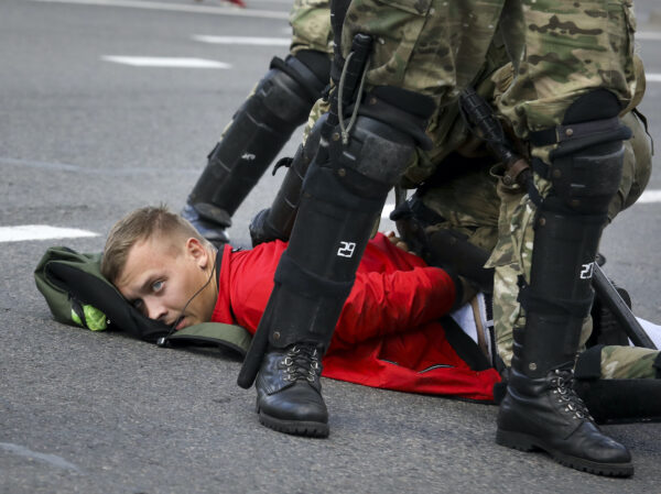 Riot police officers detain a protester