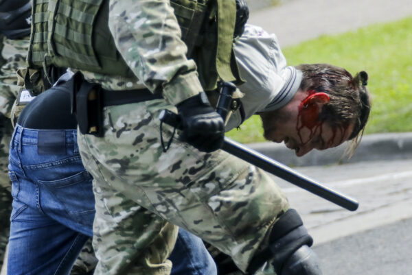 Riot police officers detain a protester