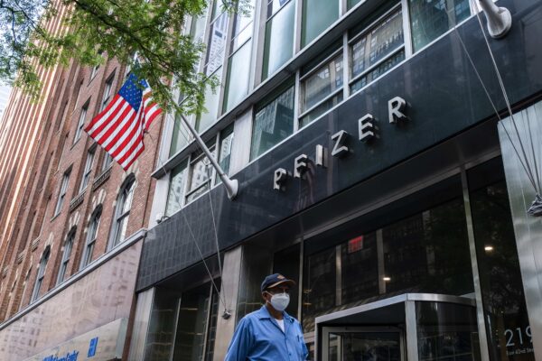 A pedestrian wearing a protective mask walks past the Pfizer headquarters in New York City