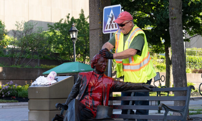 Ivan Mcguigan, of the Charlottetown Public Works department, cleans Sir John A Macdonald statue in Charlottetown after red paint was dumped on the statue on Friday June 19, 2020.The canadian Press/John Morris