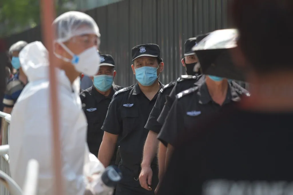 Security guards wait in line to undergo COVID-19 coronavirus swab tests at a testing station in Beijing on June 30, 2020. (Greg Baker/AFP via Getty Images)