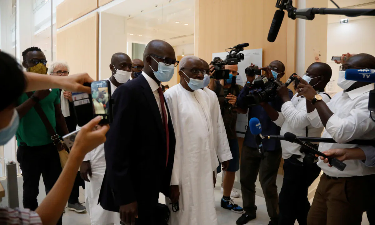 Former President of the International Association of Athletics Federations (IAAF) Lamine Diack is surrounded by journalists as he arrives with his lawyer Simon Ndiaye for the verdict in his trial at the Paris courthouse, France, on Sept. 16, 2020. (Charles Platiau/Reuters)