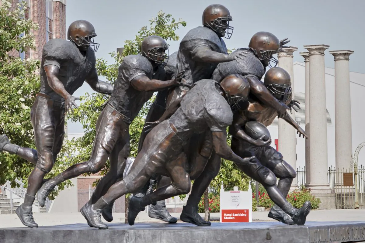 A hand sanitizing station is placed behind a statue of football players outside Memorial Stadium in Lincoln, Neb., on, Sept. 15, 2020. (Nati Harnik/AP Photo)