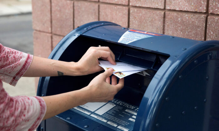 An individual deposits letters into a U.S. Postal Service collection mailbox in Philadelphia, Penn., on Aug. 14, 2020. (Rachel Wisniewski/Reuters)