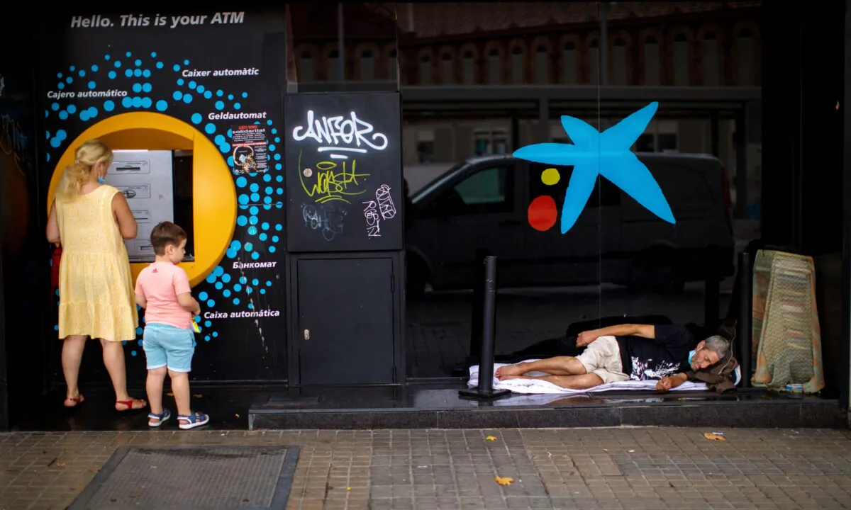 A child looks at a man sleeping outside a CaixaBank brach office in Barcelona, Spain, on July 17, 2020. (Emilio Morenatti/ AP Photo)