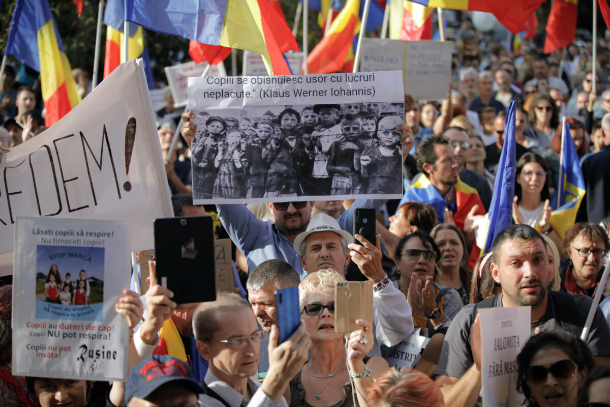 A man holds a banner showing children in a concentration camp and a paraphrase from a statement by Romanian President Klaus Iohannis that reads "Children get used to unpleasant things easily" during a protest in Bucharest, Romania, on Sept. 19, 2020. (Vadim Ghirda/AP Photo)