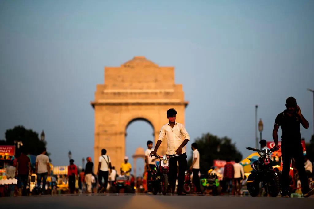 A vendor (C) wearing a mask looks for customers to ride his toy bike along the Rajpath street near India Gate in New Delhi on Sept. 16, 2020. (Jewel Samad/AFP via Getty Images)