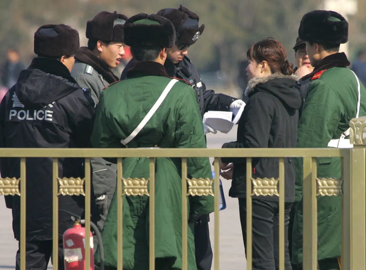 Police and paramilitary guards surround a woman while a policeman reads her petition amid tightened security on Tiananmen Square in Beijing on March 6, 2007. (FREDERIC J. BROWN/AFP via Getty Images)