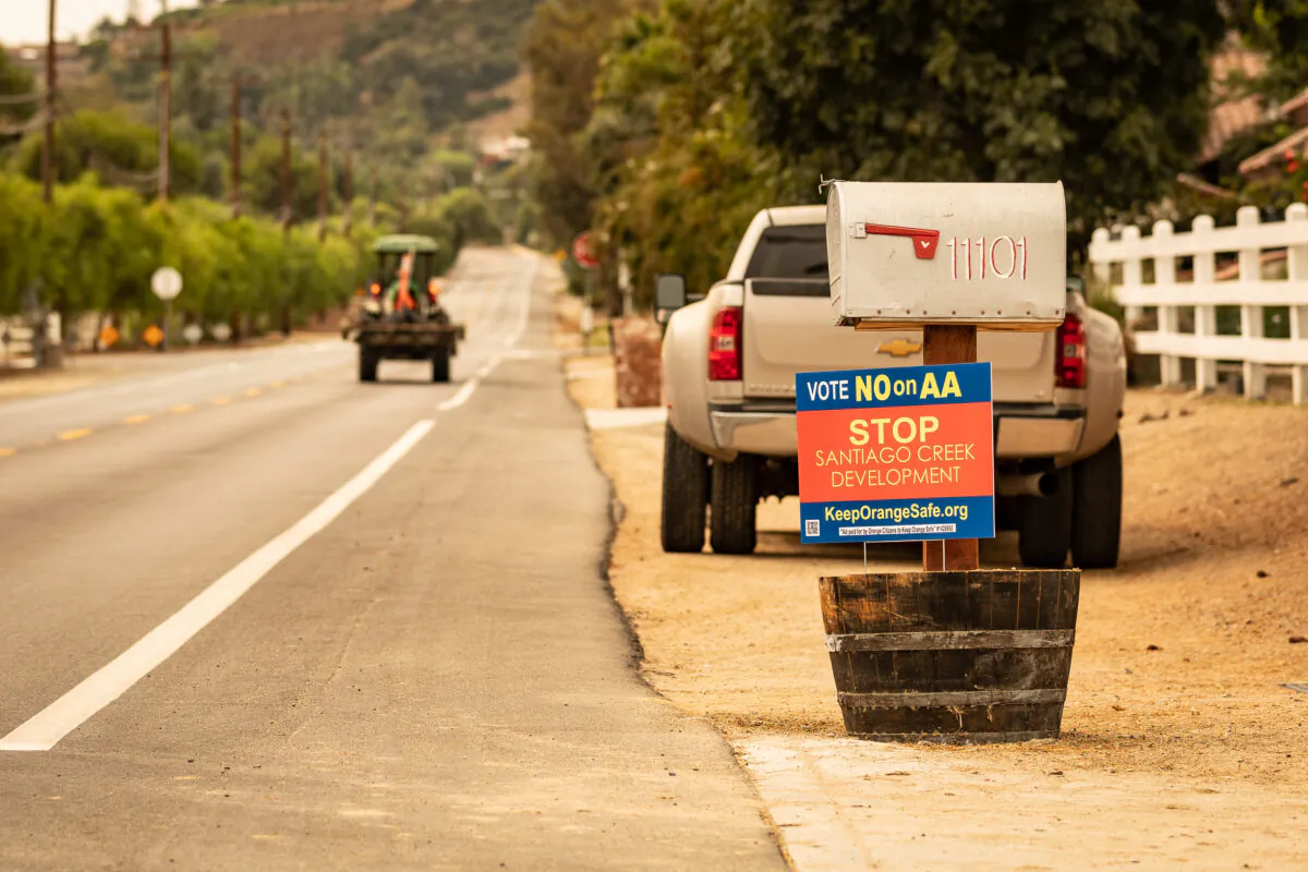 A tractor drives by a sign that urges voters to vote no on Measure AA, in front of a house in Orange, Calif., on Sept. 10, 2020. (John Fredricks/The Epoch Times)