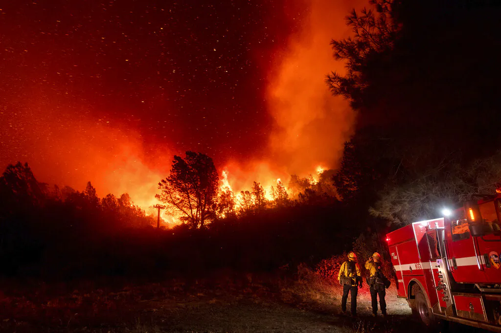 Firefighters watch the Bear Fire approach in Oroville, Calif., on Wednesday, Sept. 9, 2020. The blaze, part of the lightning-sparked North Complex, expanded at a critical rate of spread as winds buffeted the region.They work 50 hours at a stretch and sleep on gymnasium floors. Exploding trees shower them with embers. They lose track of time when the sun is blotted out by smoke, and they sometimes have to run for their lives from advancing flames. Firefighters trying to contain the massive wildfires in Oregon, California and Washington state are constantly on the verge of exhaustion as they try to save suburban houses, including some in their own neighborhoods. (AP Photo/Noah Berger)