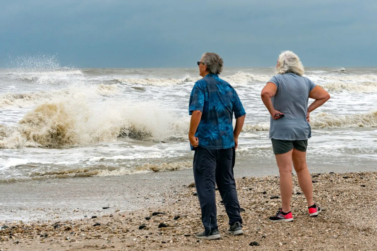 Steve and Linda Buser of Beaumont check out the rough surf on the beach near the intersection of Highway 124 and Highway 87 on the Bolivar Peninsula, Texas, on Sept. 20, 2020. (Fran Ruchalski/The Beaumont Enterprise via AP)