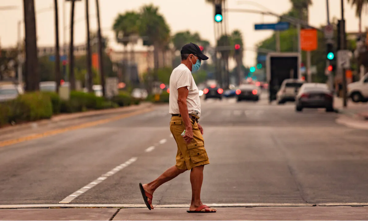 A man wearing a face mask crosses the street in Anaheim, Calif., on Sept. 9, 2020. (John Fredricks/The Epoch Times)