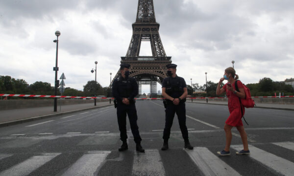 A woman walks past police officers securing the bridge leading to the Eiffel Tower