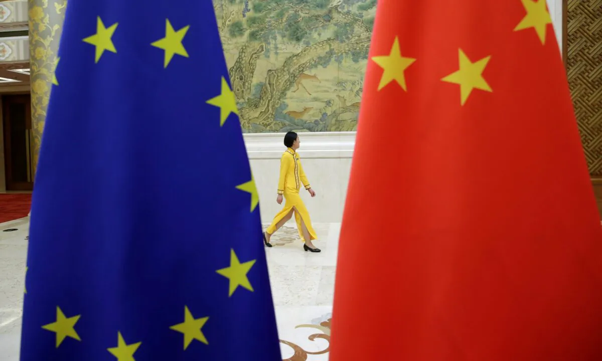 An attendant walks past flags of EU and China ahead of the EU-China High-level Economic Dialogue at Diaoyutai State Guesthouse in Beijing, on Jun. 25, 2018. (Jason Lee/REUTERS)