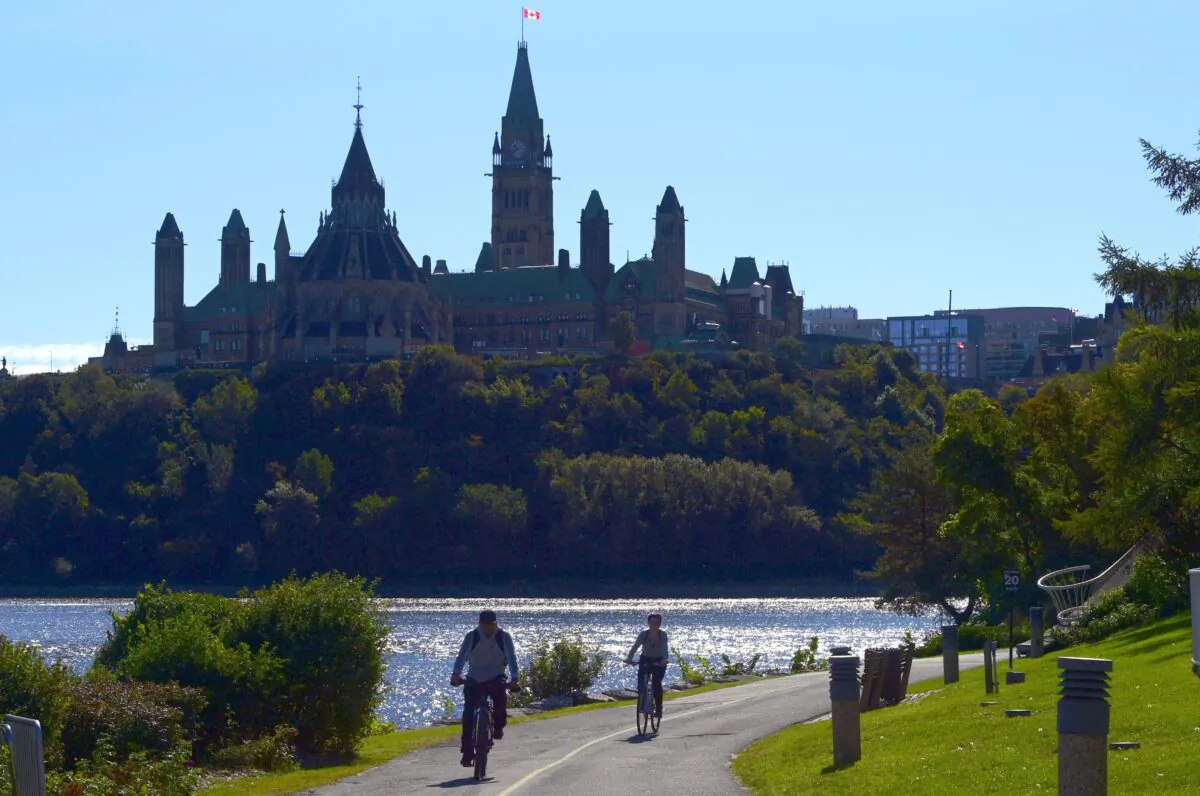 Cyclists ride along the Ottawa River as Parliament Hill looms in the background on Sept. 18, 2020. (The Canadian Press/Sean Kilpatrick)