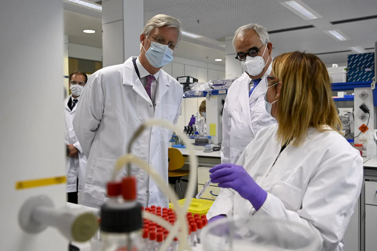 King Philippe of Belgium (L) and Janssen Pharmaceutica chief scientific officer Paul Stoffels (C) talk to a scientist at work in the laboratory during a royal visit to the headquarters of Janssen Pharmaceutica in Beerse, Belgium, on June 17, 2020. (Dirk Waem/BELGA MAG/AFP via Getty Images)