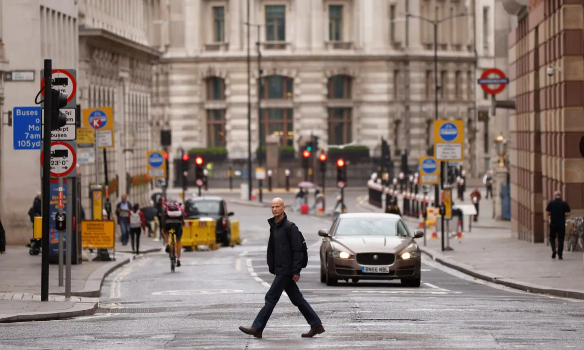 A man crosses the road in the City of London financial district amid the outbreak of the CCP virus, in London, on Sept. 23, 2020. (John Sibley/Reuters)