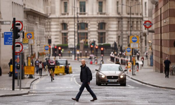 在冠状病毒病爆发期间，一名男子在伦敦金融城金融区过马路