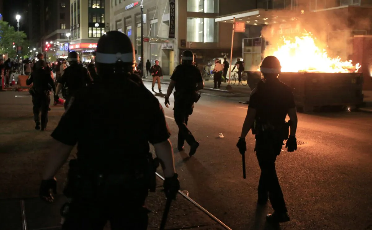 New York Police Department (NYPD) officers walk past a dumpster fire in front of the Hampton Inn in New York City on May 31, 2020. (Justin Heiman/Getty Images)