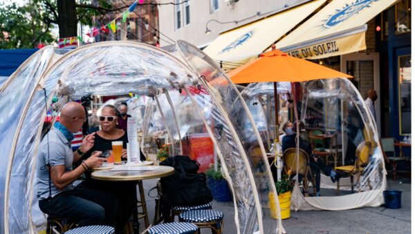 People sit under bubble tents