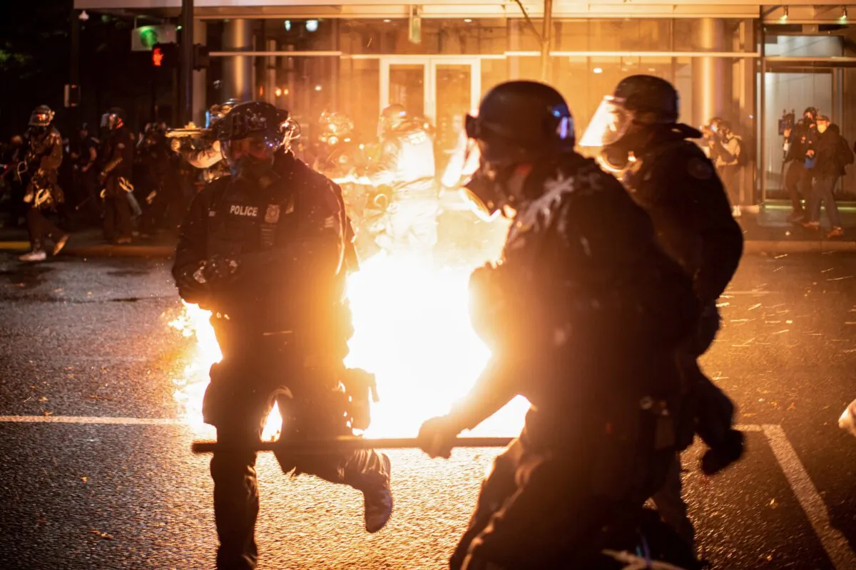 Portland police officers evade a Molotov cocktail amid rioting in Portland, Oregon. (Mathieu Lewis-Rolland/Reuters)