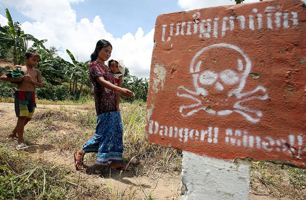 A Cambodian woman carrying a baby walks by landmine awareness sign at O'Chhoeu Kram village in the former Khmer Rouge's stronghold Pailin near the Thai border. (Tang Chhin Sothy/AFP via Getty Images)