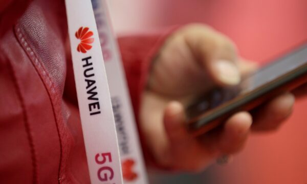 An attendee wears a badge strip with the logo of Huawei