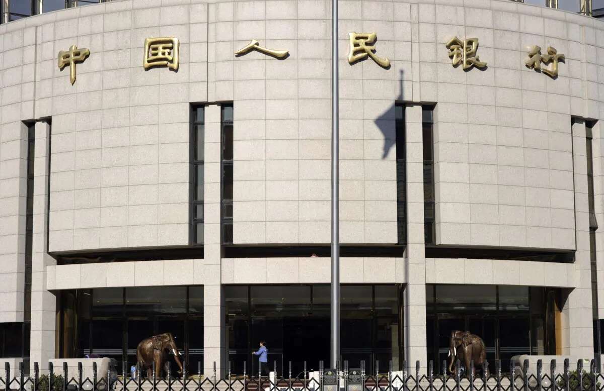 A worker cleans the entrance of the headquarters of the People's Bank of China in Beijing on Dec. 9, 2011. (LIU JIN/AFP via Getty Images)