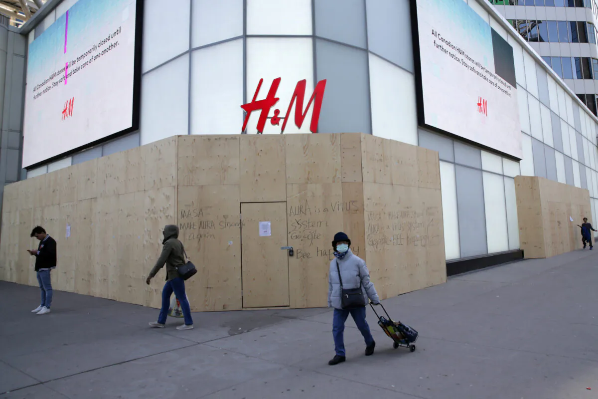 A woman wearing a protective face mask passes the closed and boarded up H&M clothing store at Eaton Centre shopping mall in Toronto on April 6, 2020, during the global outbreak of COVID-19. (REUTERS/Chris Helgren/File Photo)