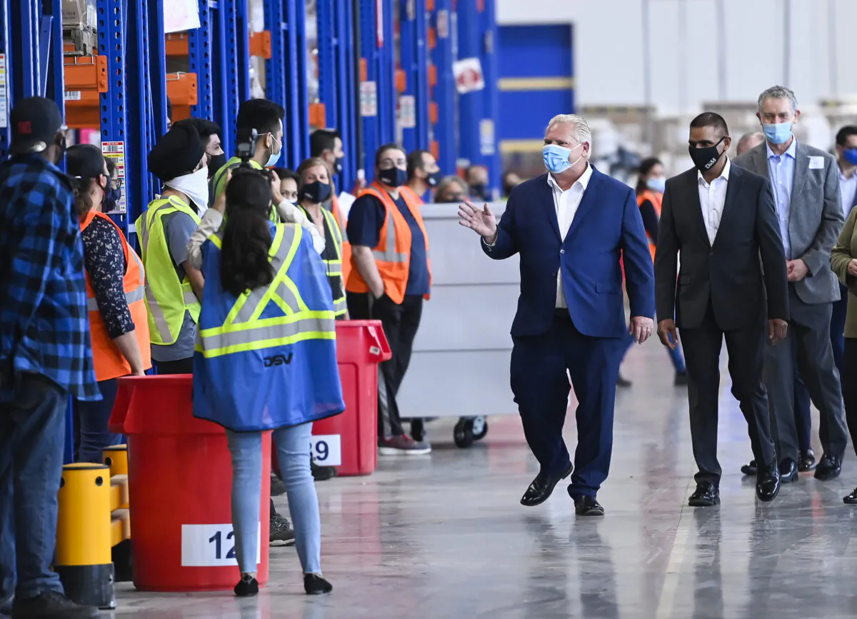 Ontario Premier Doug Ford (C) waves to workers as he tours a warehouse that ships personal protective equipment, during the COVID-19 pandemic in Milton, Ont., on Sept. 30, 2020. (The Canadian Press/Nathan Denette)