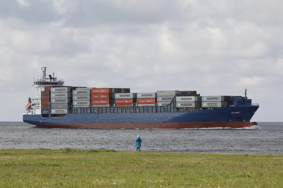 A woman watches a container ship passing by toward the harbor area of the northern German city of Cuxhaven on May 2, 2020. (Morris Mac Matzen/AFP via Getty Images)