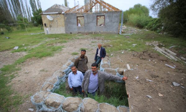 Local residents gather outside a dugout