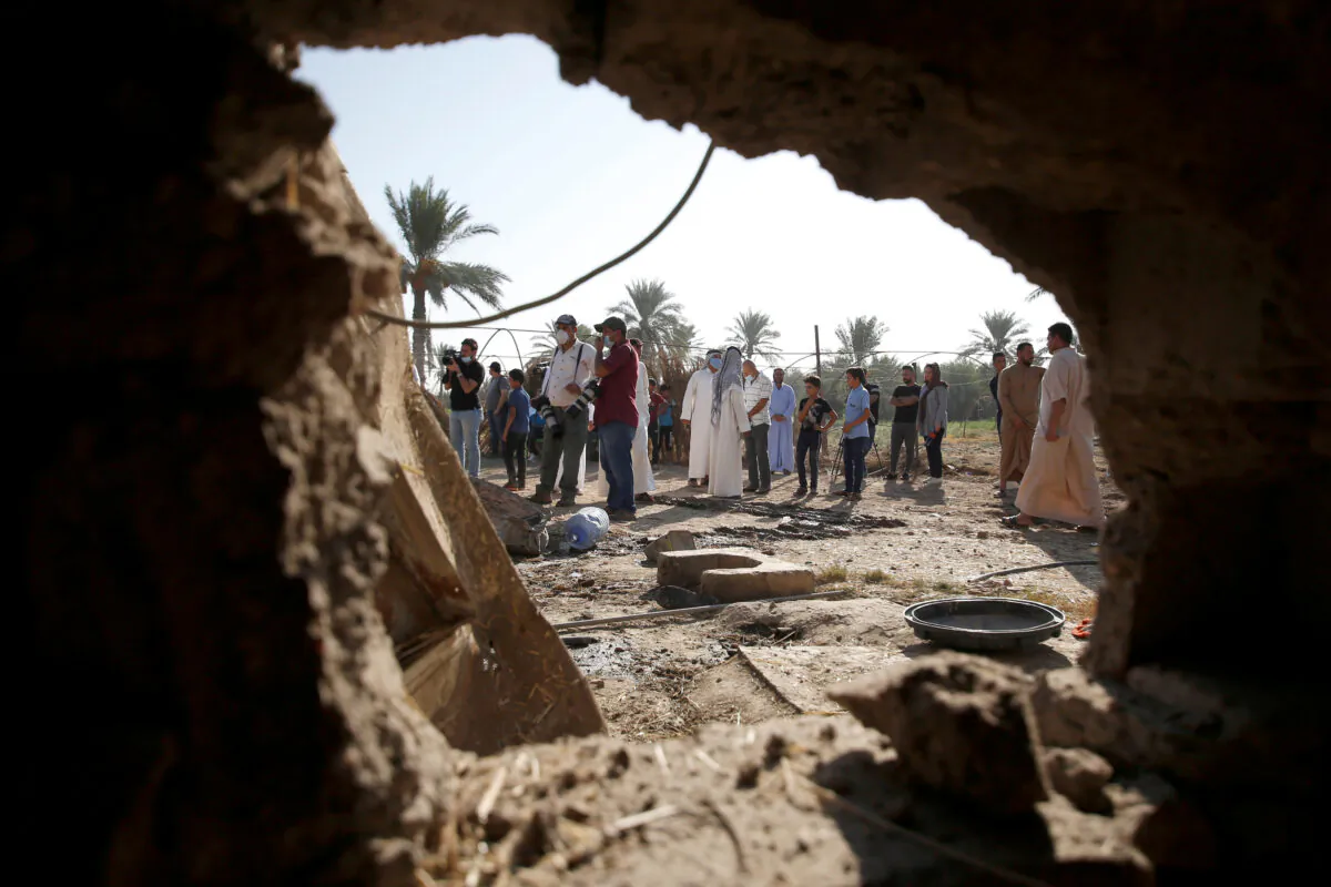 People are seen through a hole of a house damaged by a rocket attack in the Abu Ghraib district, on the outskirts of Baghdad, Iraq, on Sept. 29, 2020. (Saba Kareem/Reuters)