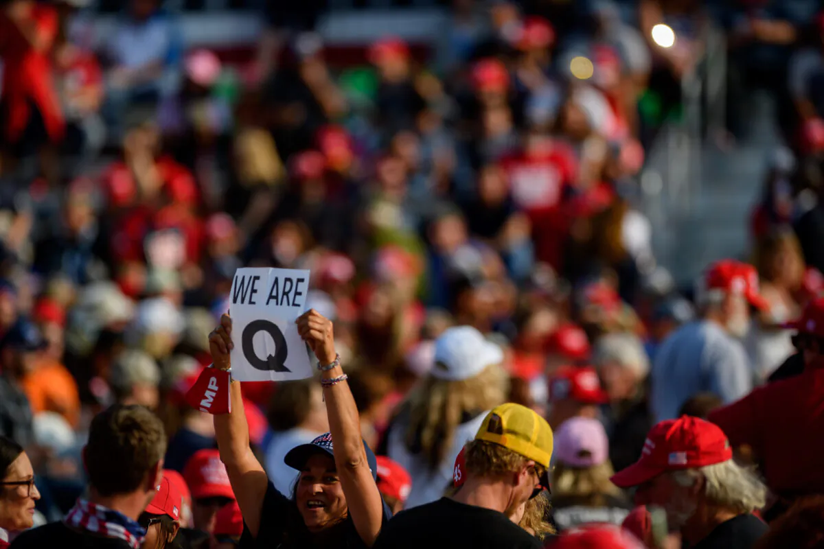A woman holds up a QAnon sign to the media as attendees wait for President Donald Trump to speak at a campaign rally at Atlantic Aviation in Moon Township, Penn., on Sept. 22, 2020. (Jeff Swensen/Getty Images)