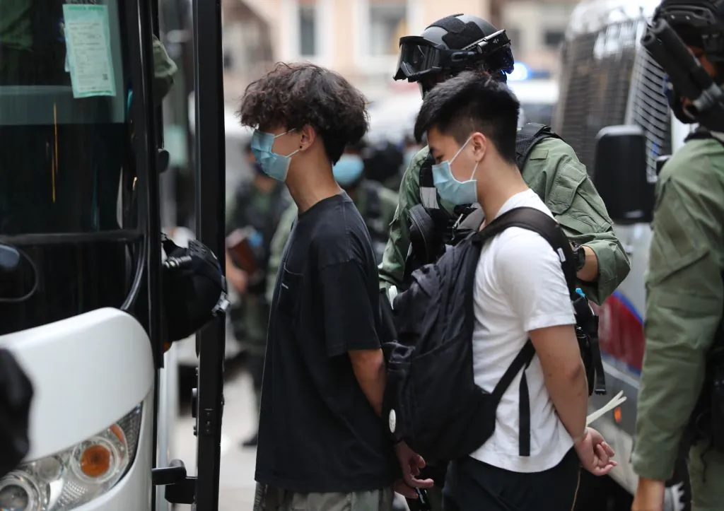 Police officers escort men into a police van following a demonstration in Hong Kong on Oct. 1, 2020. (May James/AFP via Getty Images)