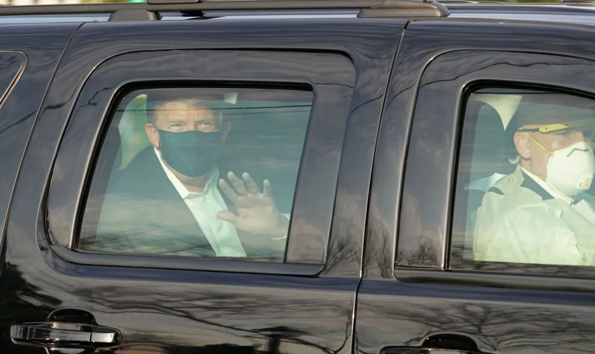 President Donald Trump waves from the back of a car in a motorcade outside of Walter Reed Medical Center in Bethesda, Md., on Oct. 4, 2020. (Alex Edelman/AFP via Getty Images)