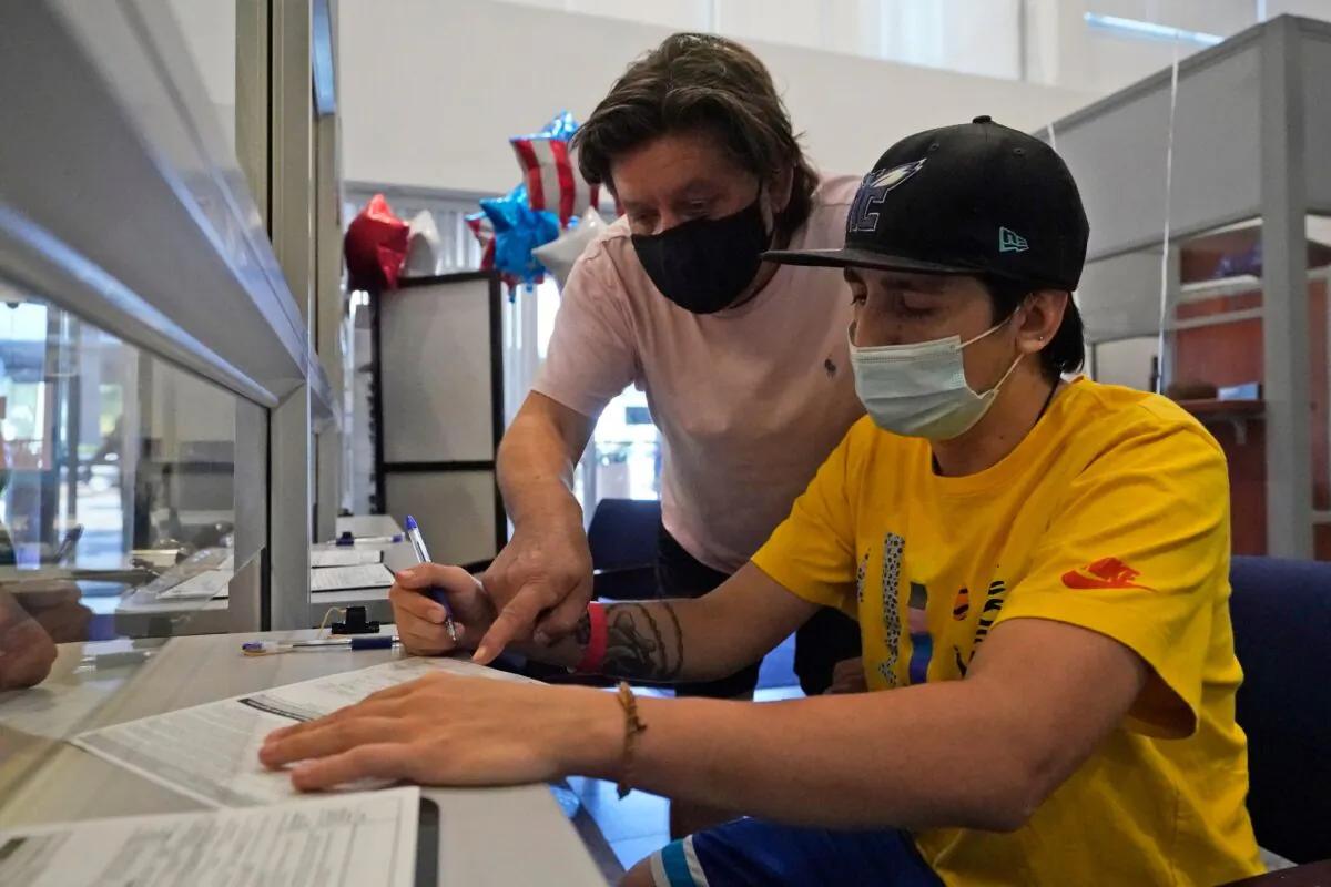 Ramiro Saez (L) helps his 22-year-old son Lucas Saez fill out a voter registration form, at the Miami-Dade County Elections Department in Doral, Fla., on Oct. 6, 2020. (Wilfredo Lee/AP Photo)
