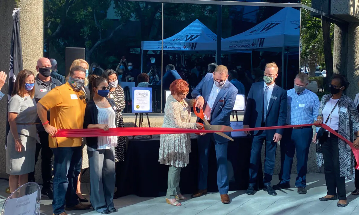 A crowd watches as Working Wardrobes CEO Jerri Rosen (L) and Board Chair Justin Frame cut the ribbon in front of a new career center in Santa Ana, Calif., on Sept. 30, 2020. (Jack Bradley/The Epoch Times)