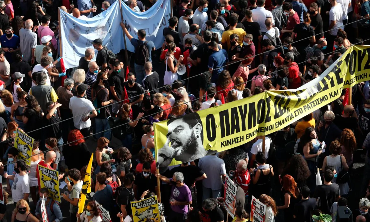 People holding a banner depicting Greek rap singer Pavlos Fyssas, who was stabbed and killed by a supporter of the Golden Dawn party in 2013, gather for a protest outside a court in Athens, on Oct. 7, 2020. (Yorgos Karahalis/AP Photo)