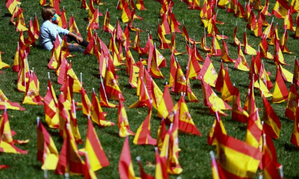 A person sits next to Spanish flags