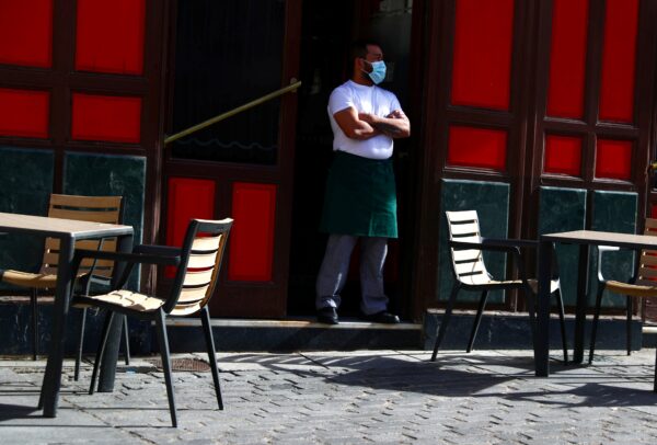 A waiter wearing a protective face mask waits for customers