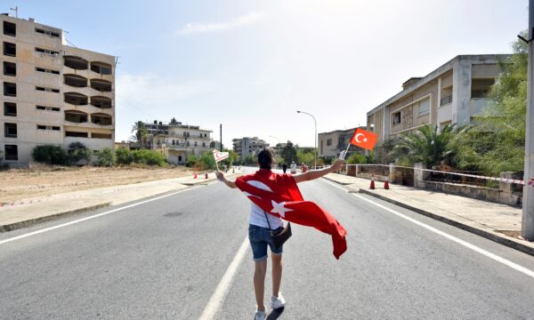 A woman walks while holding Turkish and Turkish Cypriot flags