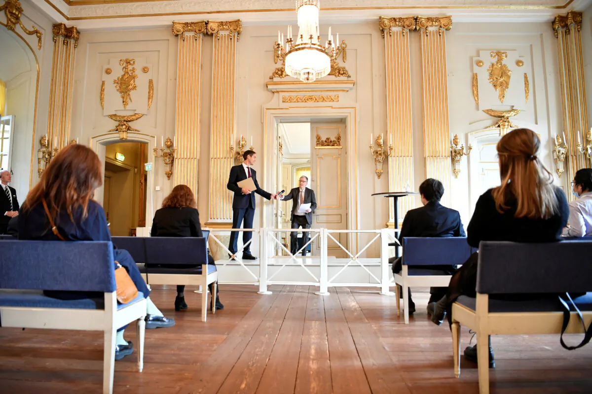 Mats Malm, Permanent Secretary of the Swedish Academy, gives the microphone to Anders Olsson, member of the academy, during the announcement of 2020 Nobel Prize in literature at Borshuset in Stockholm, Sweden on Oct. 8, 2020. (TT News Agency/Henrik Montgomery/via Reuters)